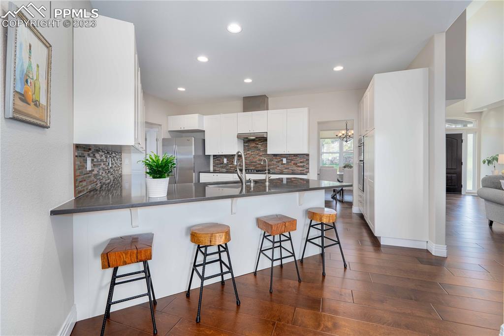 15721 South Furrow Road Larkspur, CO 80118 - Photo 22 of 50 a kitchen with stainless steel appliances granite countertop a dining table chairs refrigerator and sink