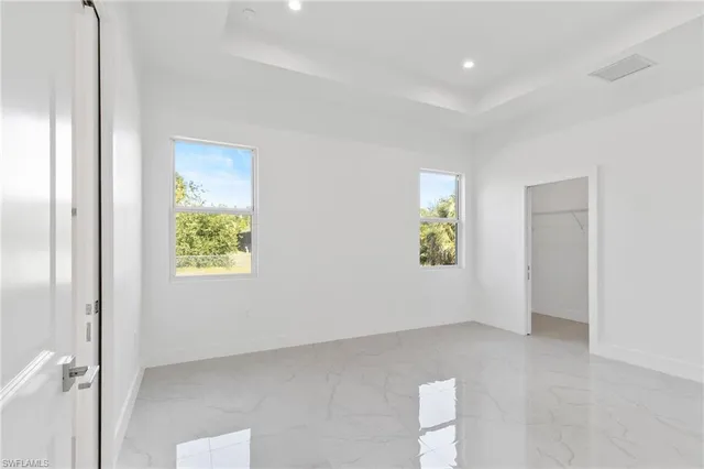 a view of an empty room with window and wooden floor