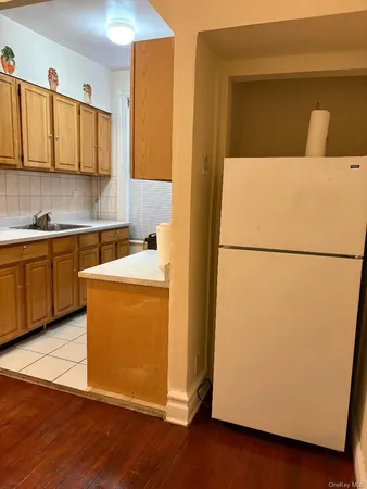 a utility room with refrigerator and a wooden floor