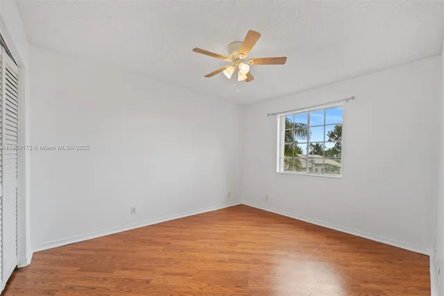 an empty room with chandelier fan and windows