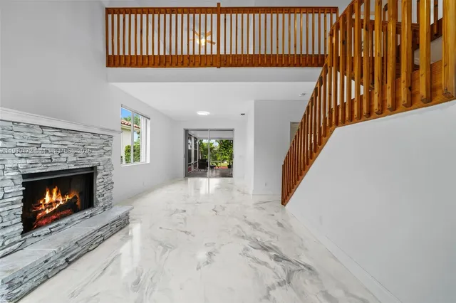 a view of an empty room with wooden floor and a fireplace