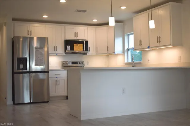 a kitchen with stainless steel appliances granite countertop a refrigerator a sink and a stove