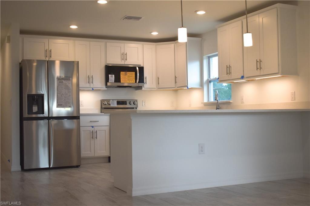 3880 Lora Street Fort Myers, FL 33916 - Photo 2 of 6 a kitchen with stainless steel appliances granite countertop a refrigerator a sink and a stove