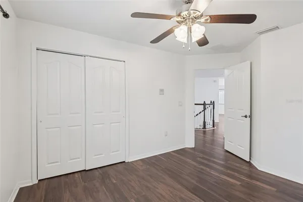an empty room with wooden floor closet fan and windows