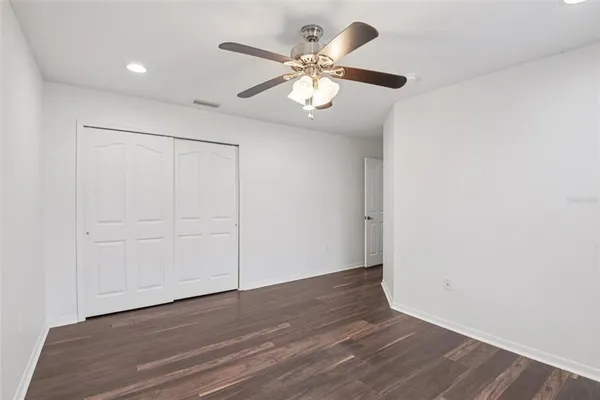 an empty room with wooden floor chandelier fan and closet area