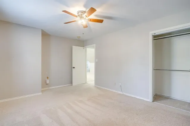 an empty room with chandelier fan and refrigerator