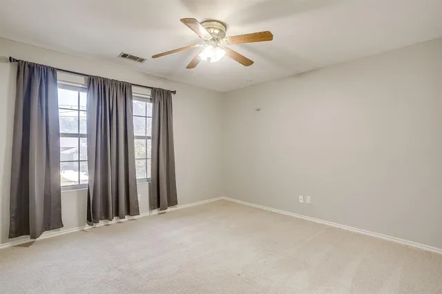 an empty room with windows and fan