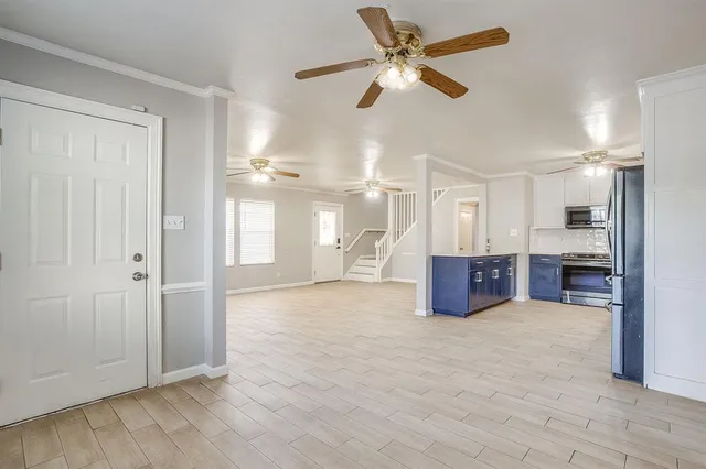 an empty room with chandelier fan and windows