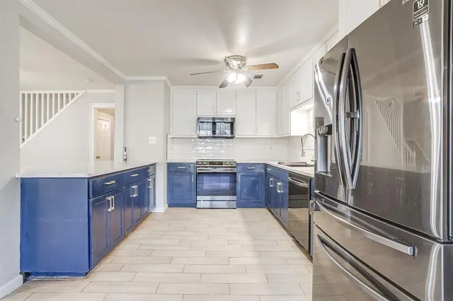 a large kitchen with stainless steel appliances a sink and a refrigerator