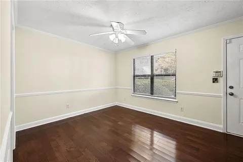 an empty room with wooden floor ceiling fan and windows