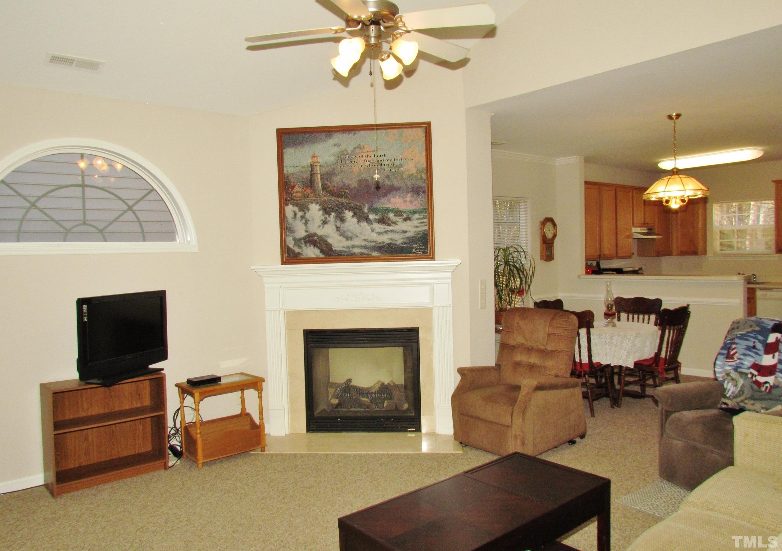 8421 Whisper Ridge Place Raleigh, NC 27613 - Photo 3 of 30 a living room with furniture a flat screen tv and a fireplace
