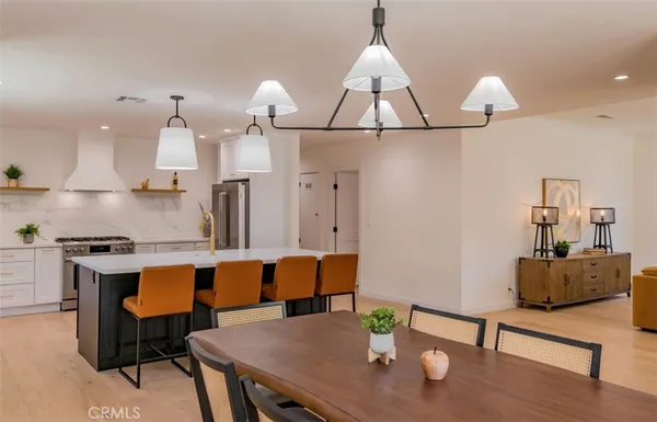 a dining room with wooden floor a chandelier a wooden table and chairs