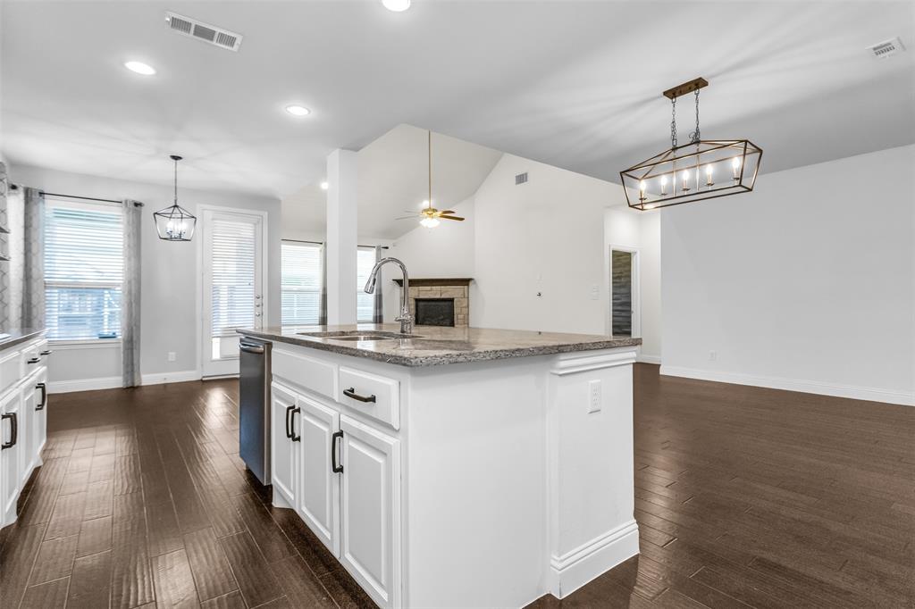 15713 Canyon Ridge Prosper, TX 75078 - Photo 19 of 38 Kitchen island featuring a granite countertop, undermount sink with gooseneck faucet, white cabinetry, and a dishwasher