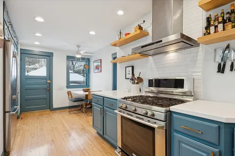 a kitchen with stainless steel appliances a stove a sink and a refrigerator with wooden floor