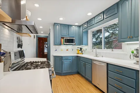 a kitchen with stainless steel appliances a sink a stove a refrigerator cabinets and a window