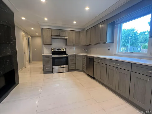 a large kitchen with stainless steel appliances granite countertop a stove and a sink