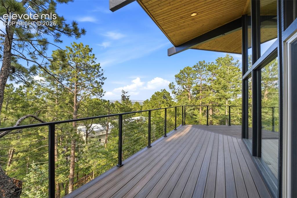 17 Pine Road Colorado Springs, CO 80906 - Photo 42 of 48 Expansive outdoor deck featuring wood-finish flooring, black metal cable railing, and floor-to-ceiling windows