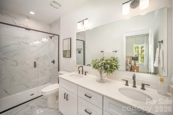 a bathroom with a double vanity sink toilet mirror and shower