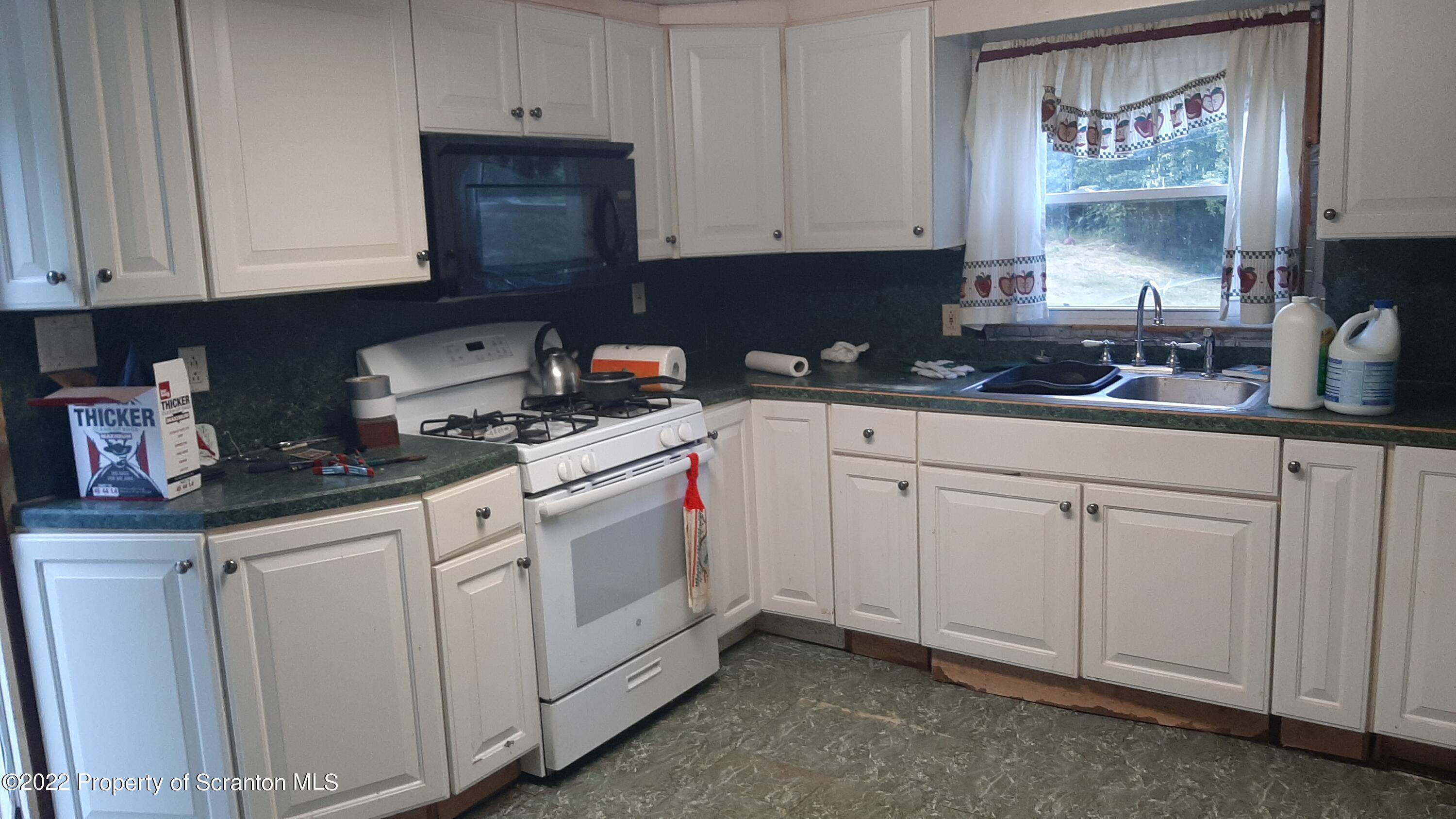 469 Bennett Road Hop Bottom, PA 18824 - Photo 4 of 25 a kitchen with white cabinets and white appliances