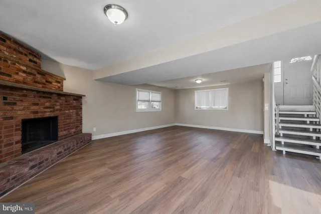 an empty room with wooden floor fireplace and windows