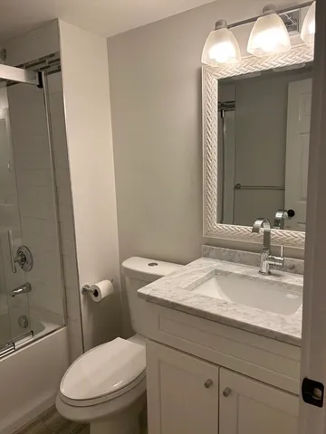 a bathroom with a granite countertop toilet sink and mirror