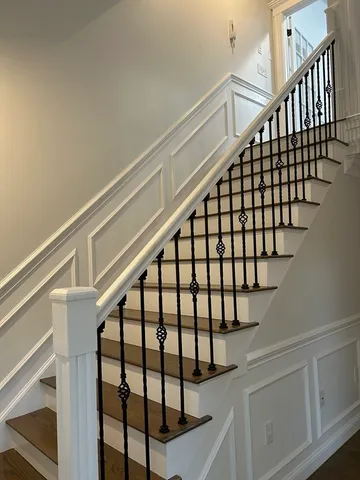 a view of staircase with wooden floor and white walls