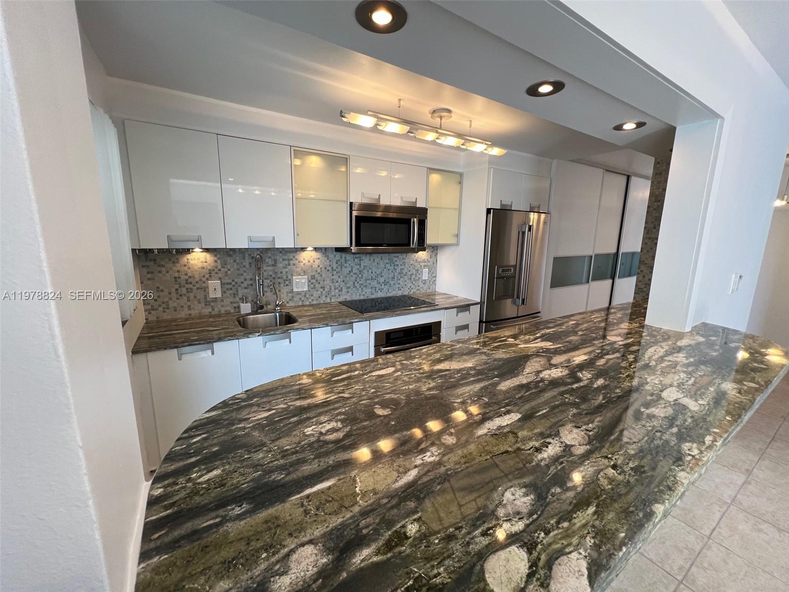 1340 Lincoln Road, Unit 705 Miami Beach, FL 33139 - Photo 10 of 21 a large kitchen with kitchen island granite countertop a refrigerator and a sink