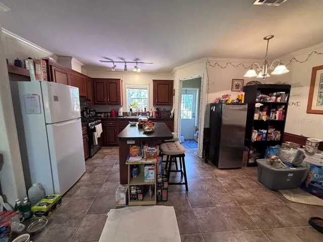 a kitchen with stainless steel appliances a refrigerator a stove a sink a dining table and chairs