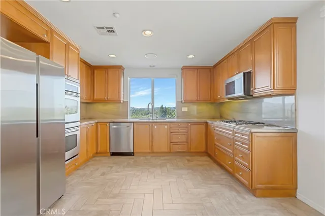 a kitchen with granite countertop a sink a counter top space stainless steel appliances and cabinets