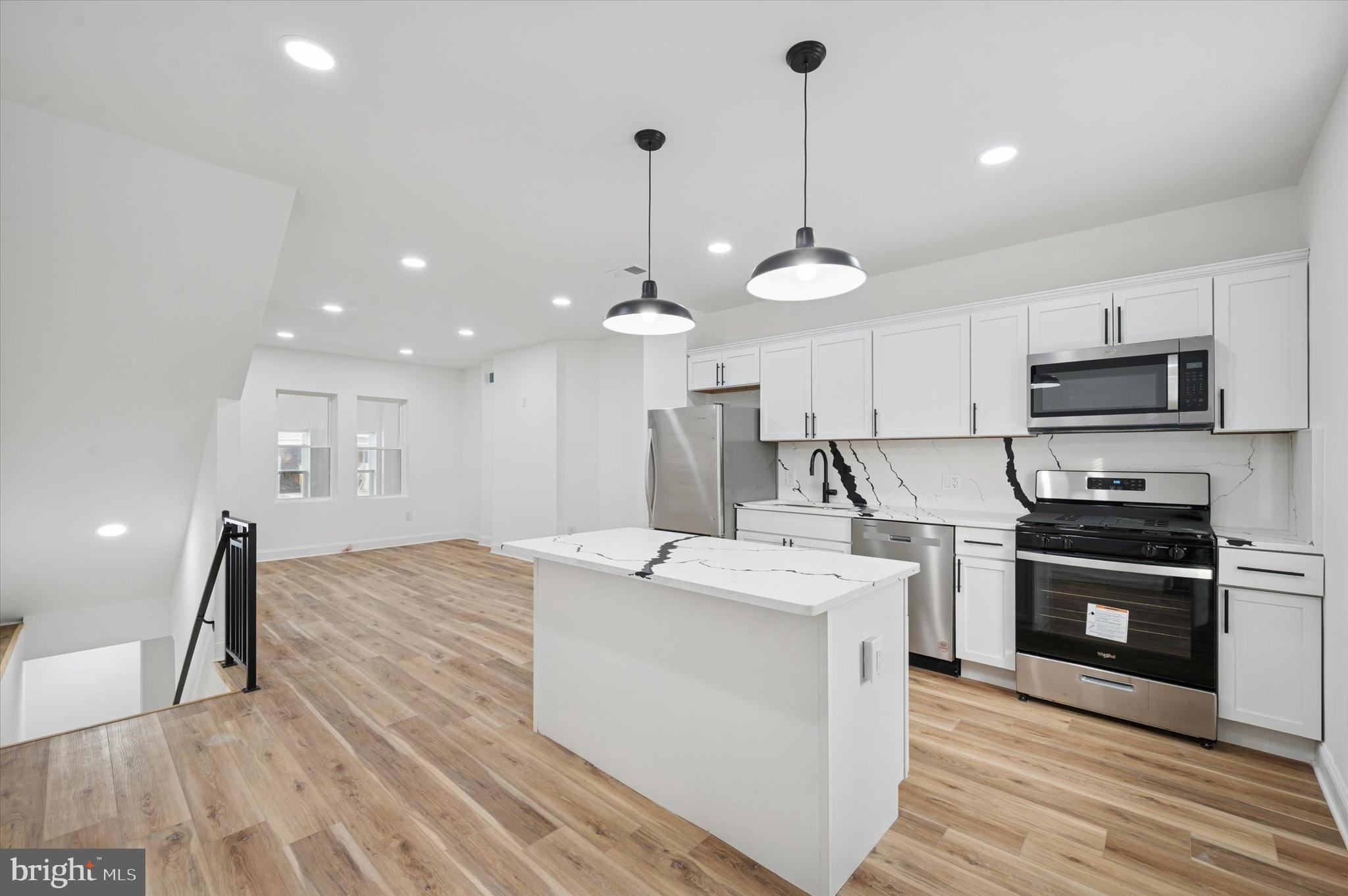 a large kitchen with kitchen island a stove a sink a center island and wooden floor