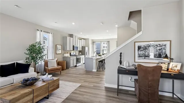 a living room with furniture potted plant and kitchen view