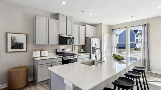 a kitchen with stainless steel appliances granite countertop a stove a refrigerator a sink dishwasher a dining table and chairs with wooden floor