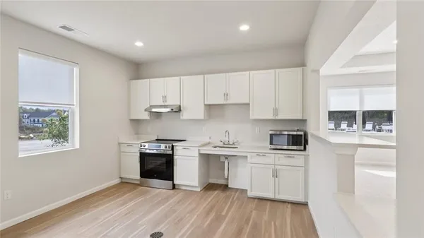 a kitchen with cabinets stainless steel appliances a sink and wooden floor