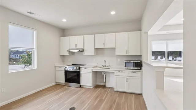 a kitchen with cabinets stainless steel appliances a sink and wooden floor