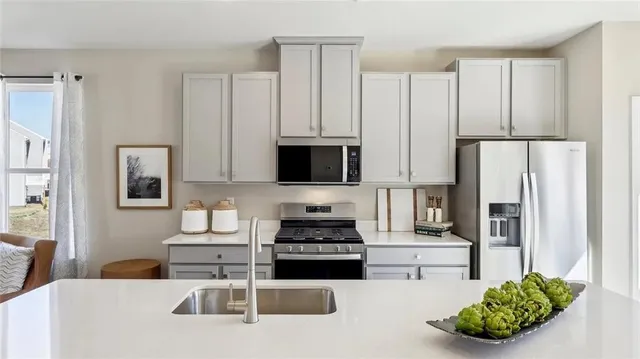 a kitchen with stainless steel appliances a stove a refrigerator a sink a stove and white cabinets