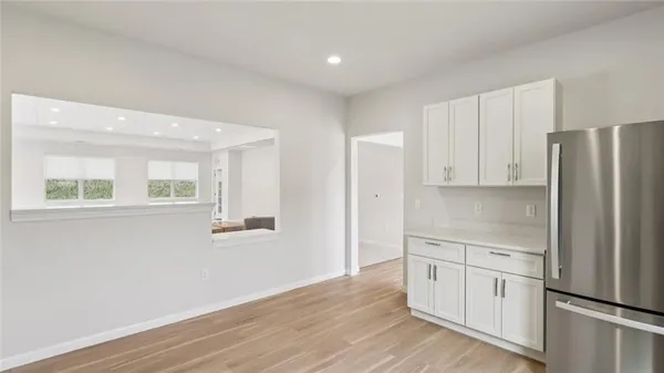 a kitchen with white cabinets and wooden floor