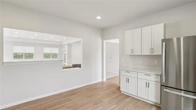 a kitchen with white cabinets and wooden floor