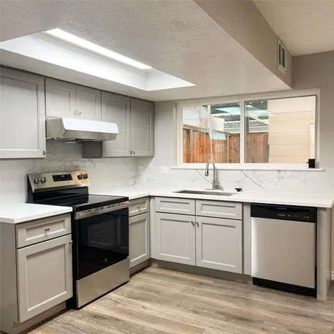 a kitchen with stainless steel appliances a sink and stove top oven