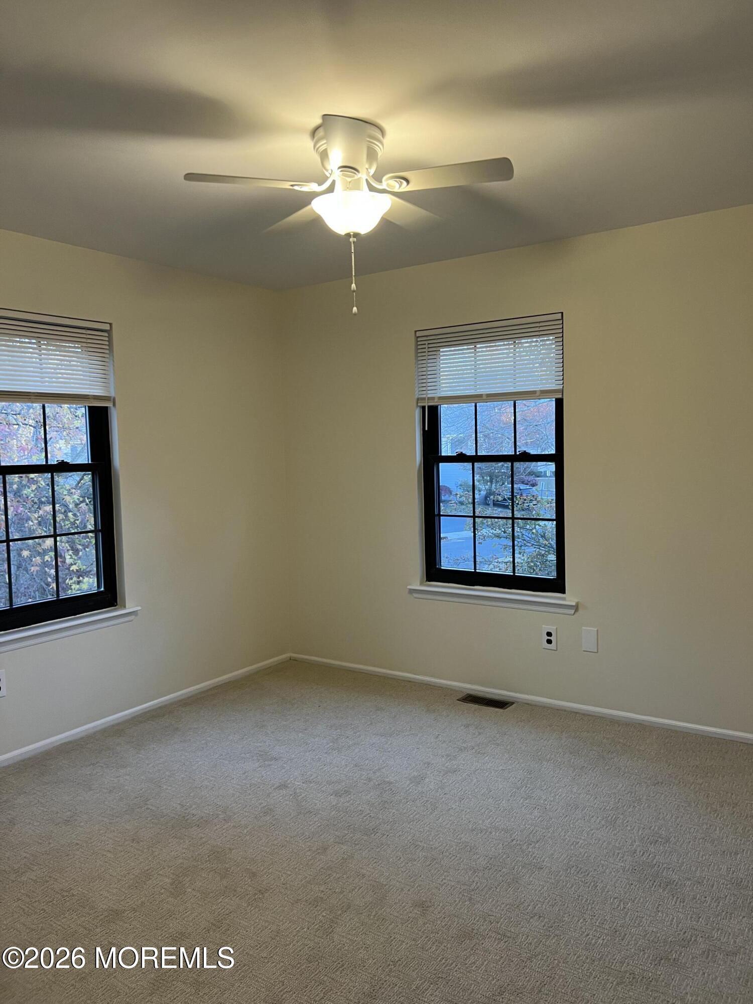 91 Paddock Court Oceanport, NJ 07757 - Photo 15 of 17 an empty room with a chandelier fan and windows