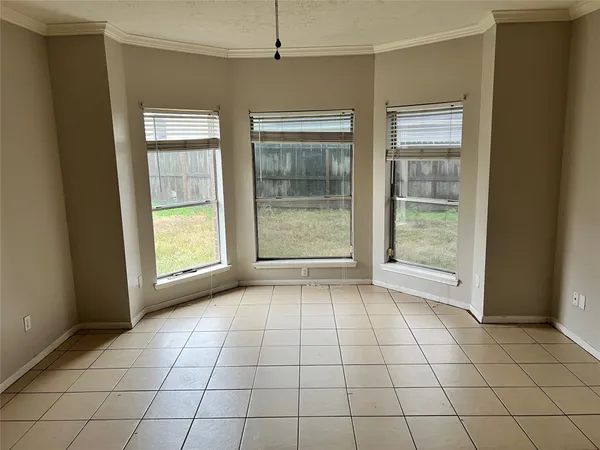 a view of an empty room with window and chandelier fan