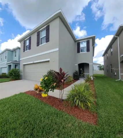 a view of an house with backyard and a tree