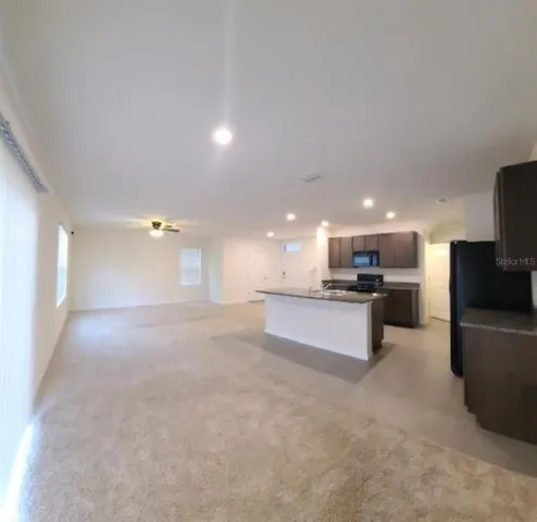 a view of kitchen with kitchen island stainless steel appliances a sink and cabinets