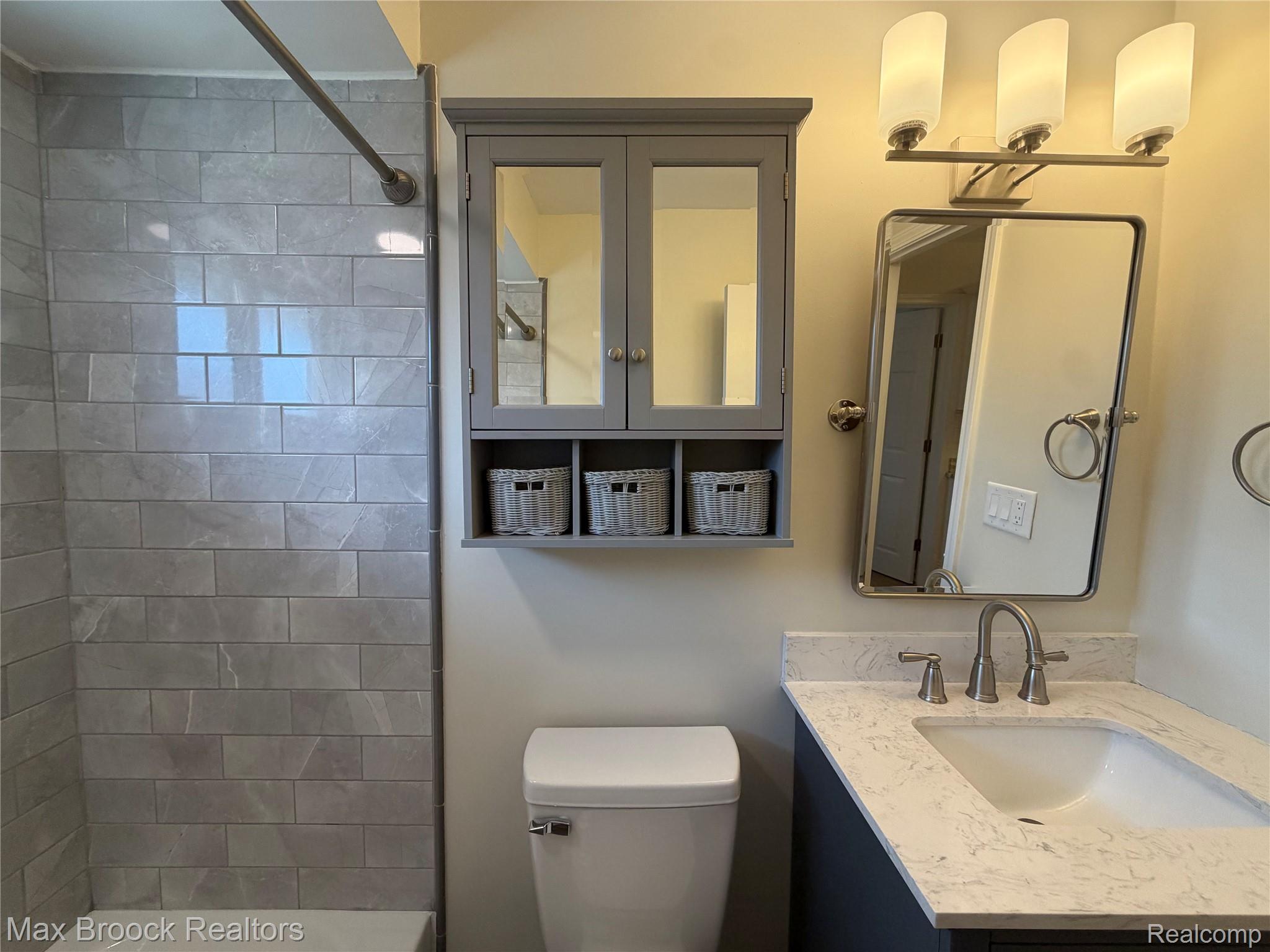 3875 Devon Road, Unit # 9 Royal Oak, MI 48073 - Photo 7 of 17 Bathroom featuring a rectangular porcelain undermount sink, a stone-finish countertop, brushed nickel faucet, and a wall-mounted medicine cabinet with open cubbies
