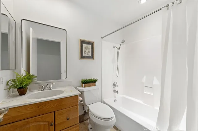 a bathroom with a sink a toilet a mirror a vanity and shower
