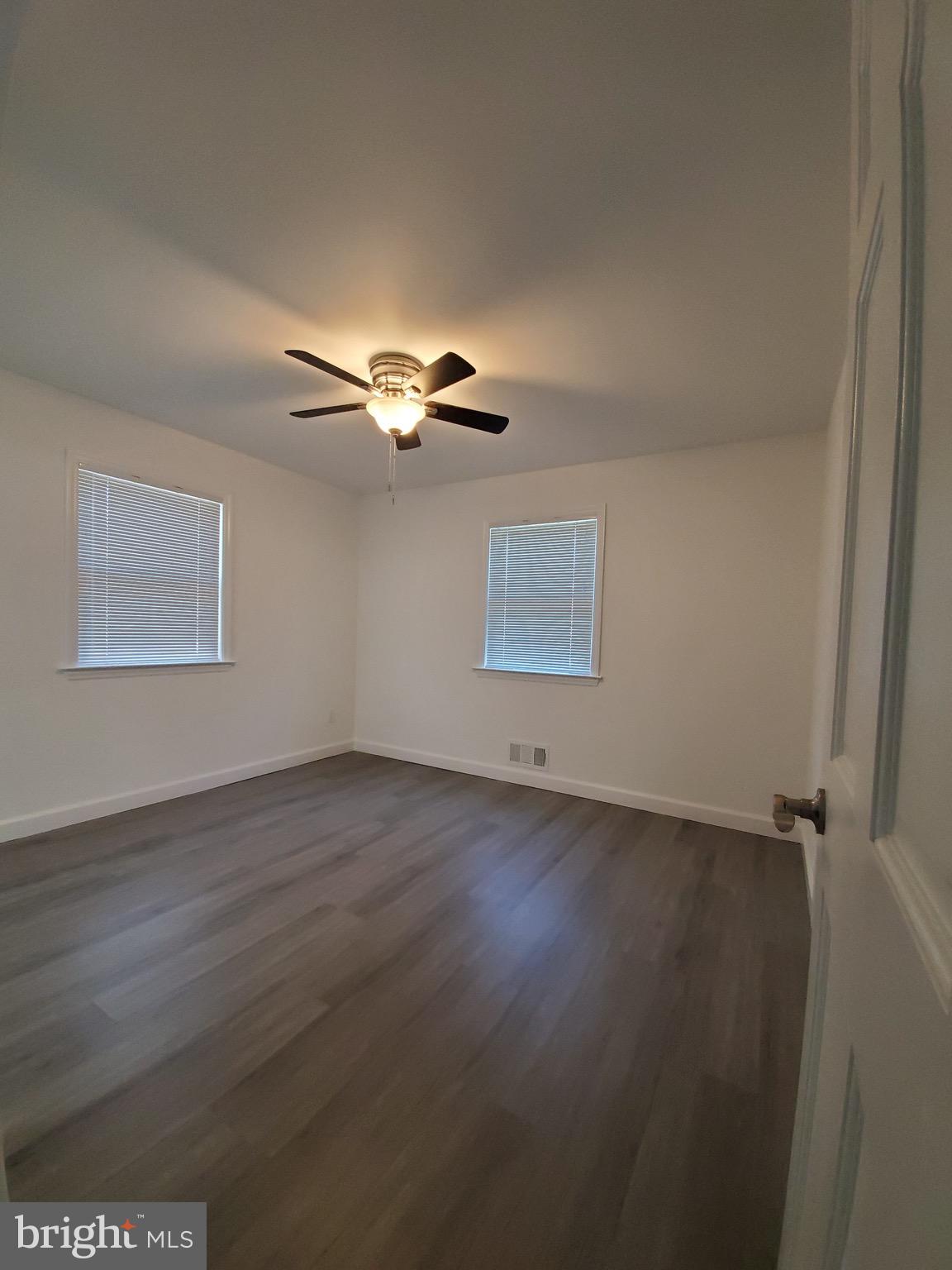8303 Brixton Street Springfield, VA 22152 - Photo 4 of 5 an empty room with wooden floor fan and windows