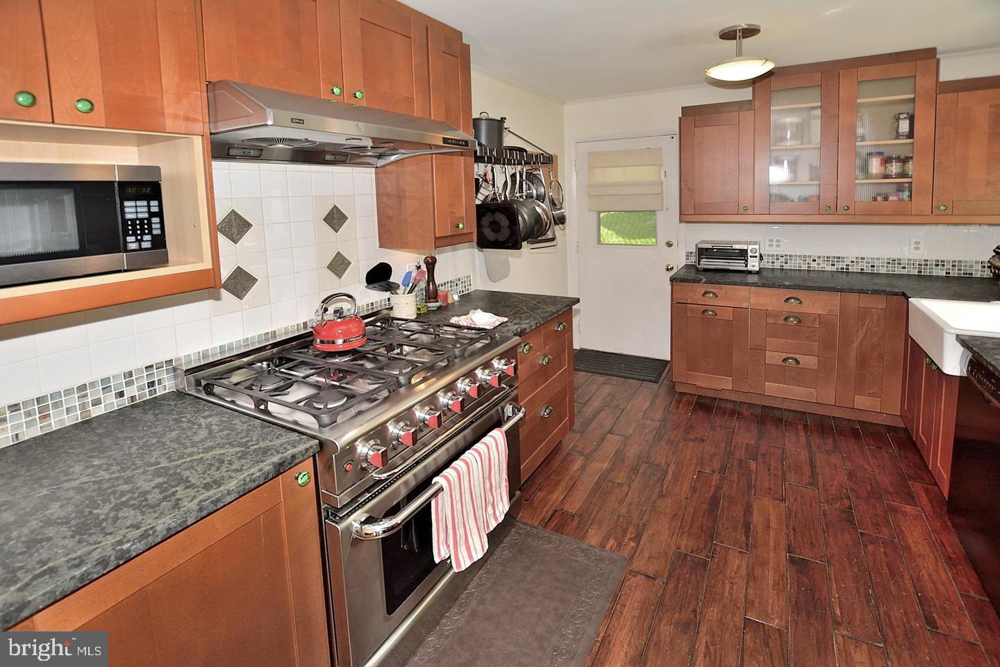 8303 Brixton Street Springfield, VA 22152 - Photo 5 of 5 a kitchen with granite countertop a stove and a wooden floors