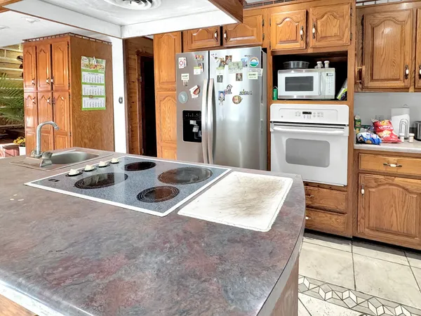 a kitchen with stainless steel appliances granite countertop a refrigerator a oven and white cabinets with wooden floors