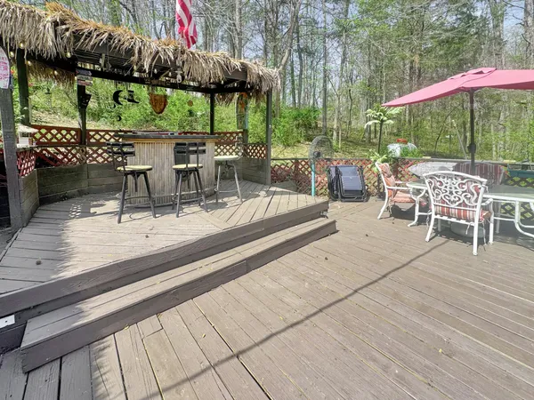 a view of a patio with a table and chairs under an umbrella with a barbeque