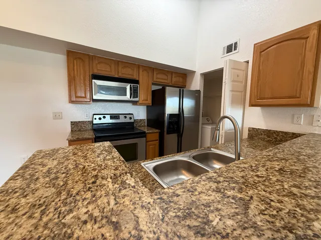 a kitchen with granite countertop a refrigerator and a stove top oven