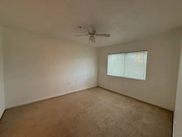an empty room with a window and a ceiling fan
